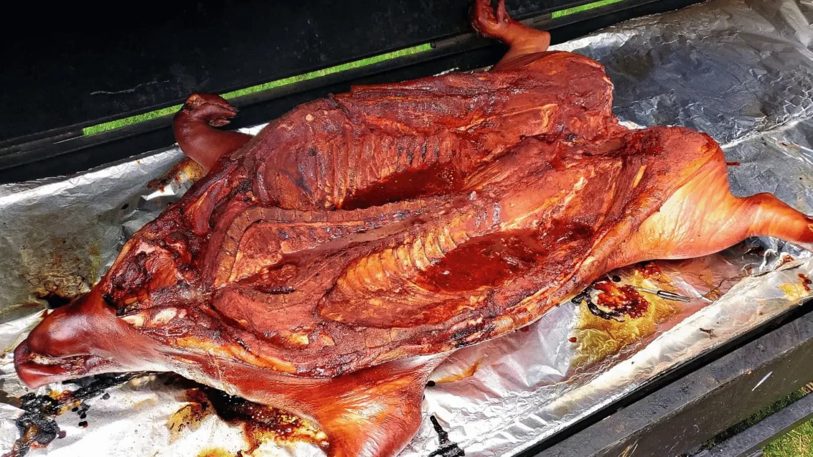 A whole pig roasting Brazilian style over a grill for a large cookout.