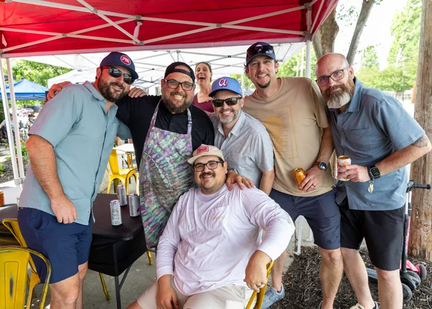 Mark Frazie and a group of friends under a market tent at Frazie's third anniversary party, smiling at the camera.