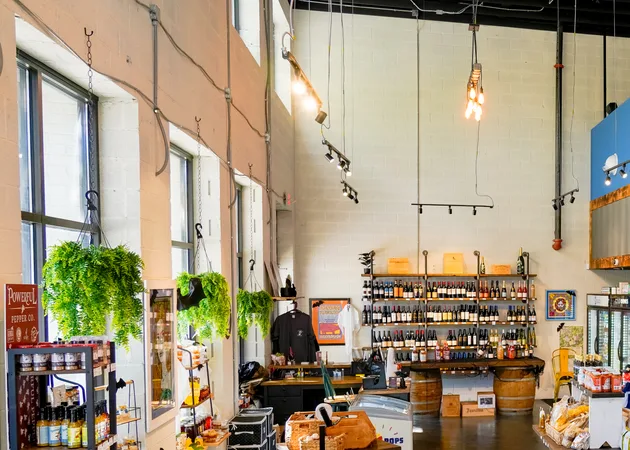 Inside the market at Frazie's: hanging plants, a wall of wine and shelves of pantry goods under the tall windows.