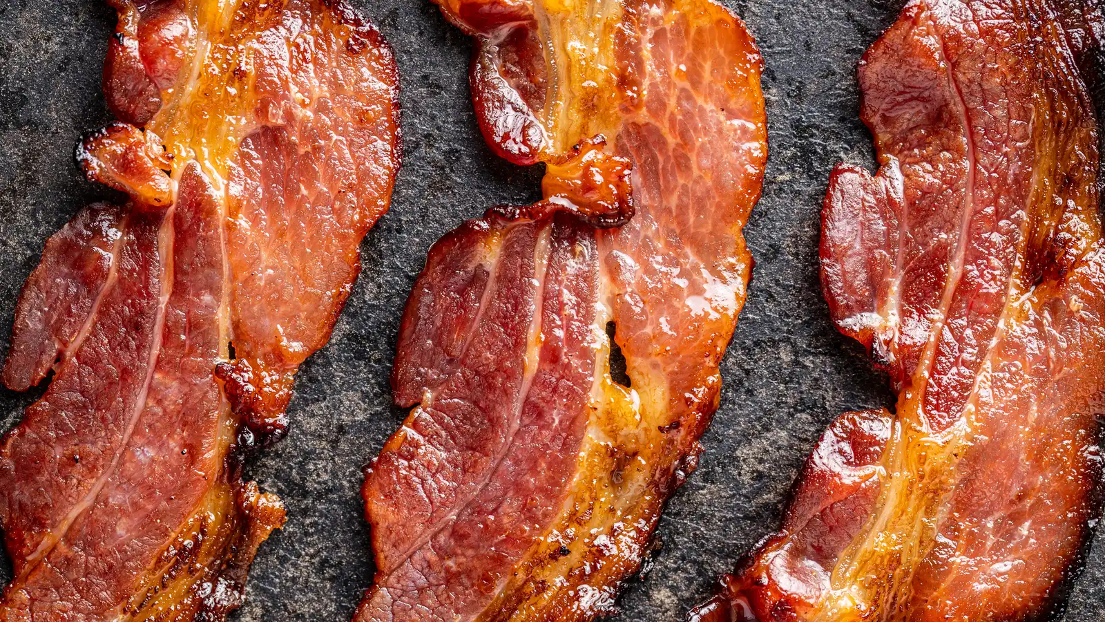 Crispy beef bacon strips just off the heat, rendered and browned with the fat gone glassy at the edges.